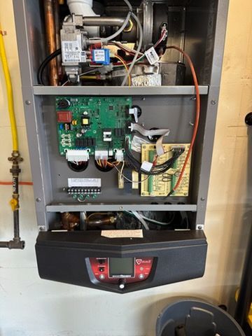 Open boiler with exposed circuit boards and wiring in a utility closet