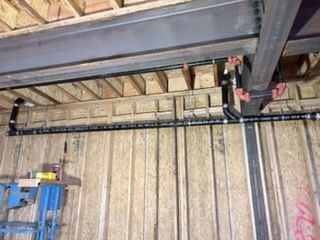 Ceiling view of exposed metal beams and wiring in an unfinished industrial space
