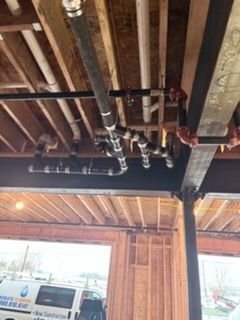 Underside of a wooden ceiling with exposed pipes and valves in a garage or workshop