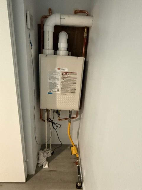 Wall-mounted boiler and exposed pipes in a small utility closet