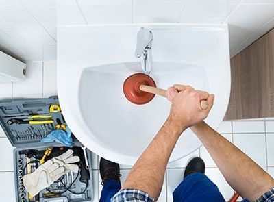 Male Plumber Using Plunger in Bathroom Sink — Fort Myers, FL — Panther Plumbing Inc.