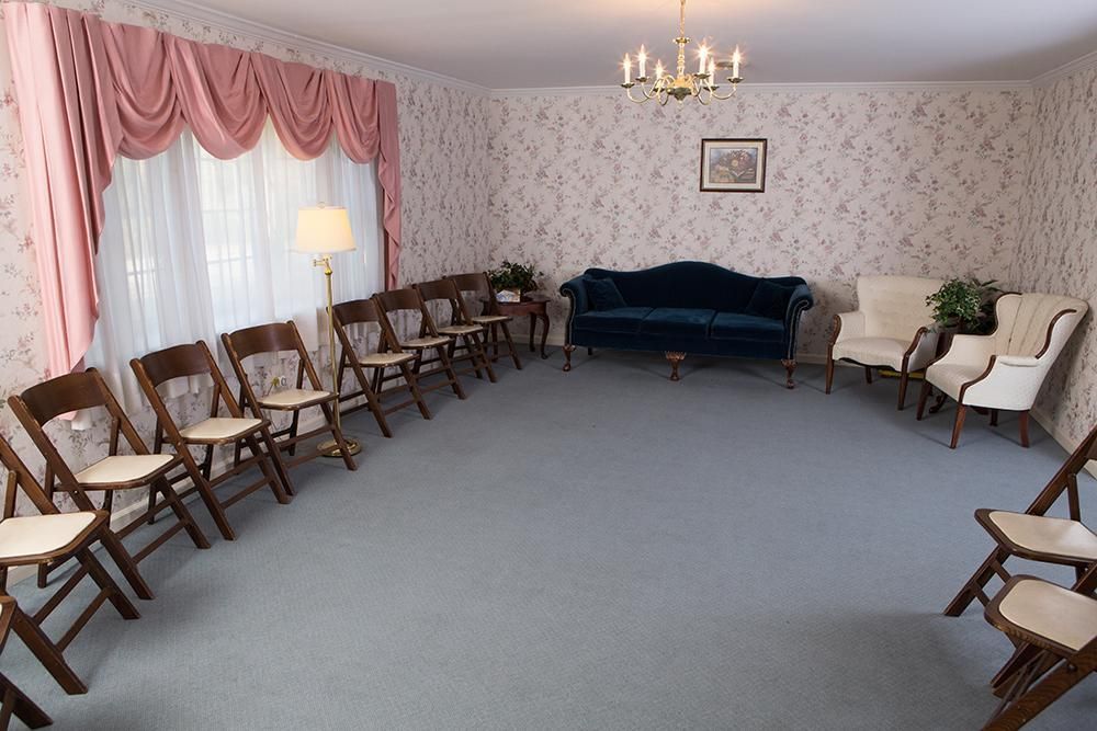 A living room with a couch , chairs , and a chandelier.