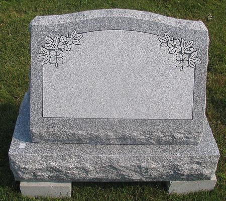 A gravestone with flowers carved into it is sitting in the grass.