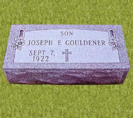 A gravestone for joseph e gouldener is sitting on top of a lush green field.