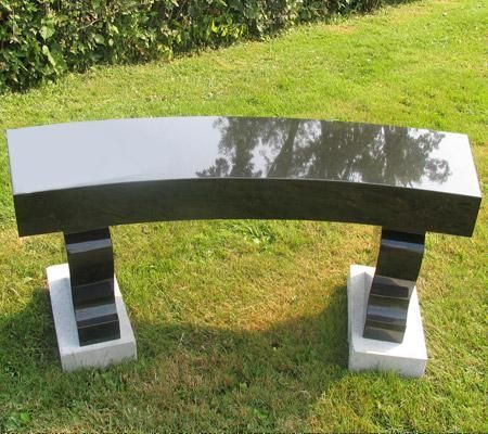 A black stone bench is sitting in the grass