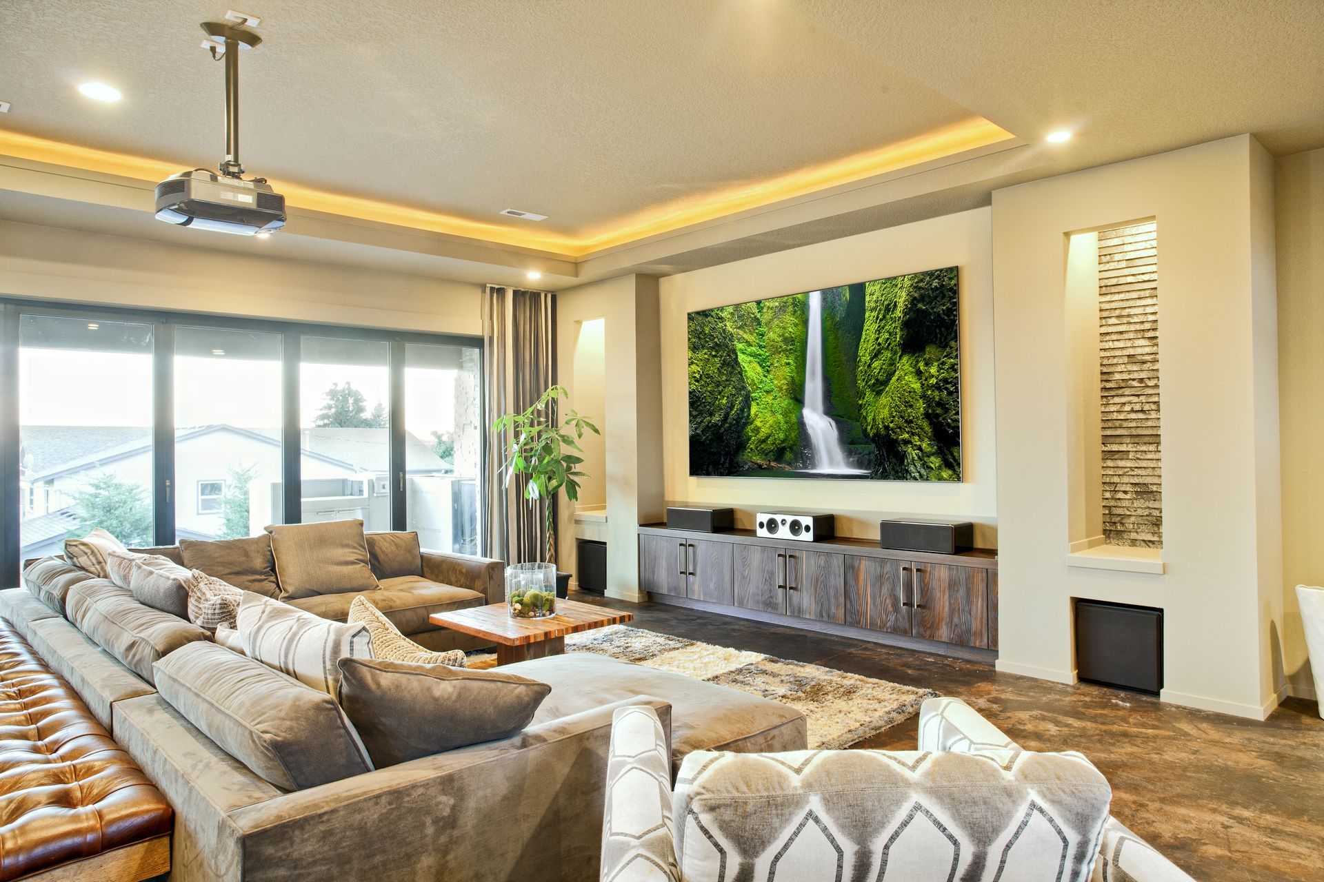 A living room with a large couch and a projector screen on the wall.