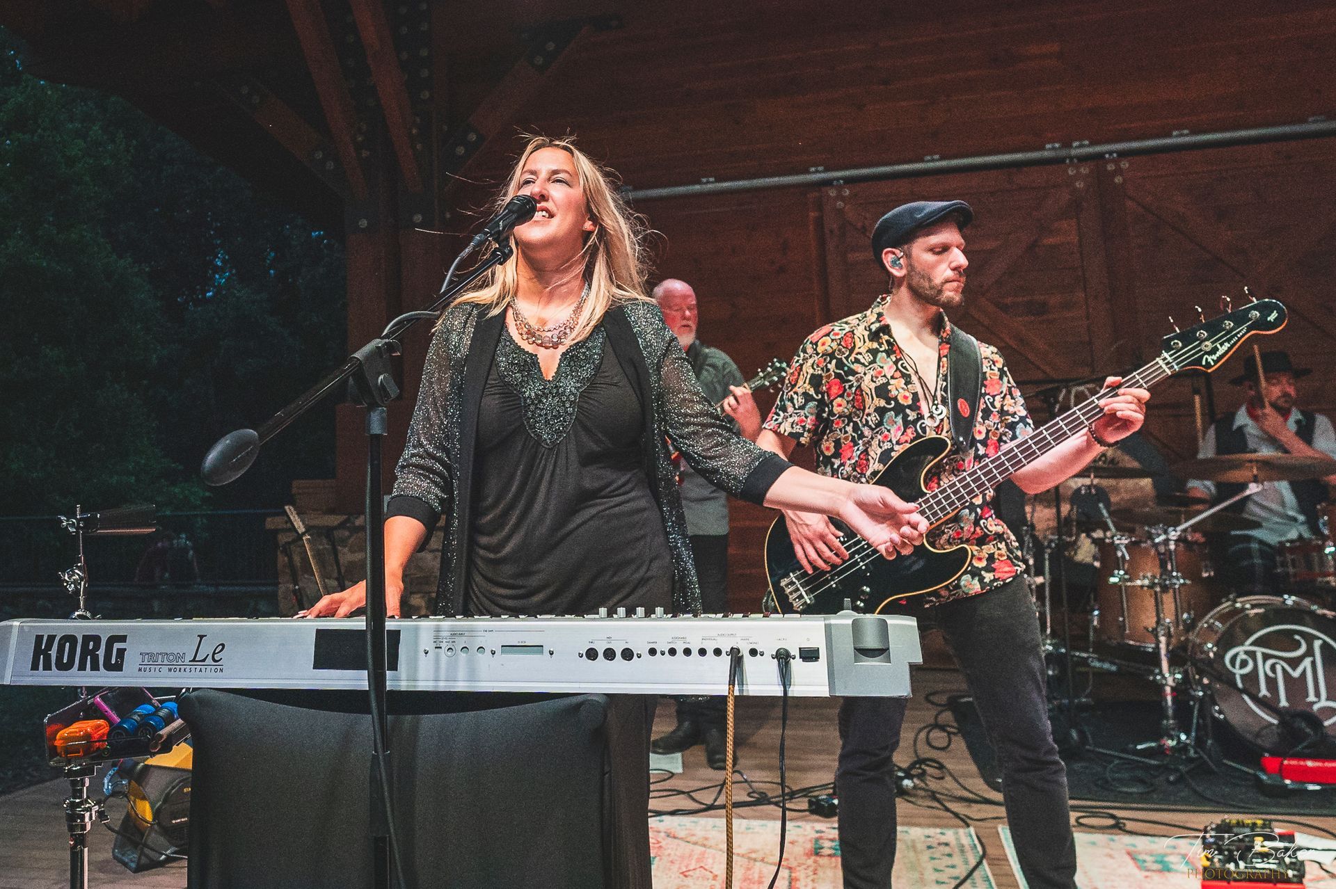 A band performs on stage: female singer on keyboard, guitarist, drummer, and other band members visible.