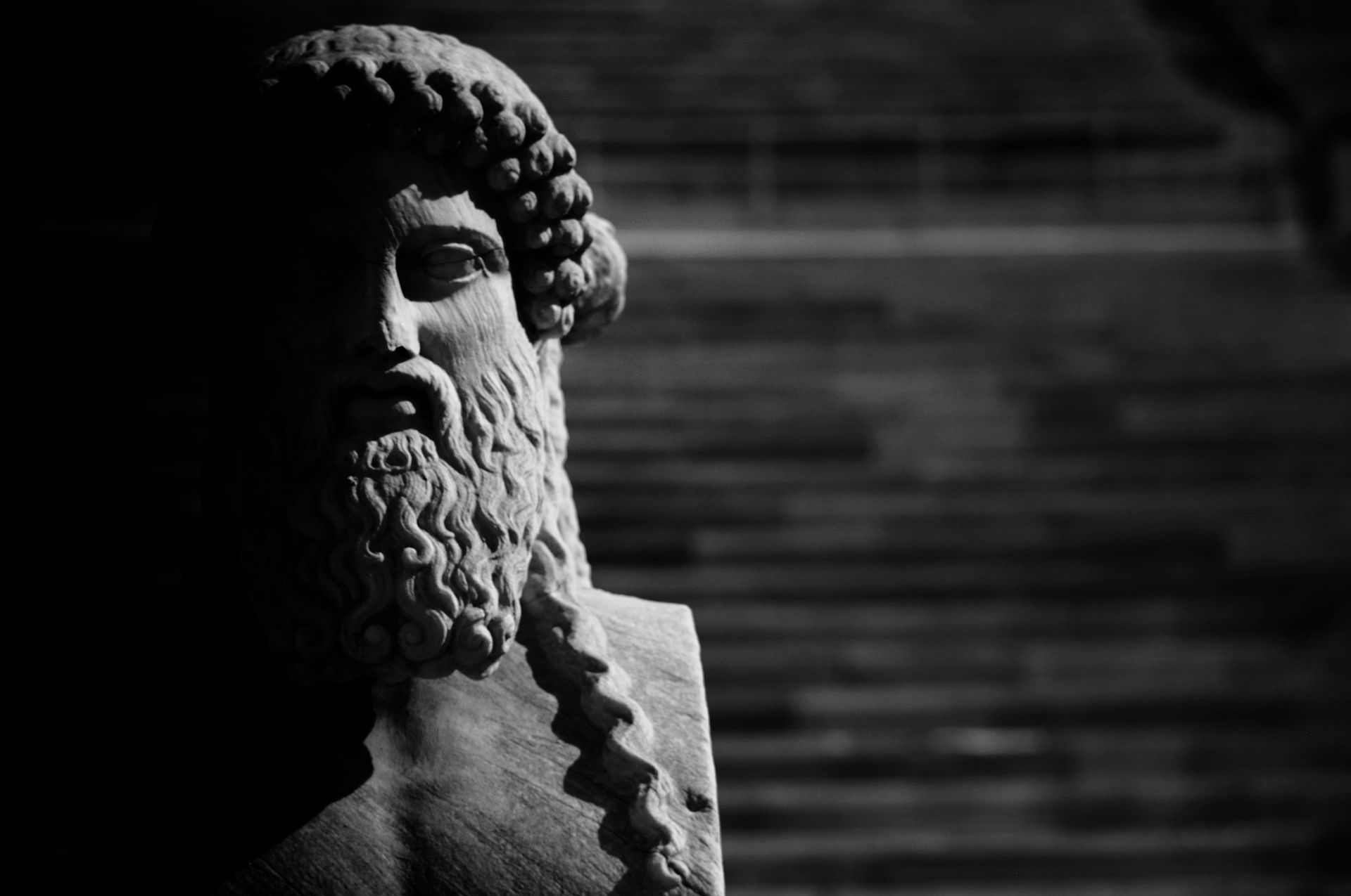 Busto en blanco y negro de un hombre barbudo con cabello rizado; vista parcial, iluminación dramática.