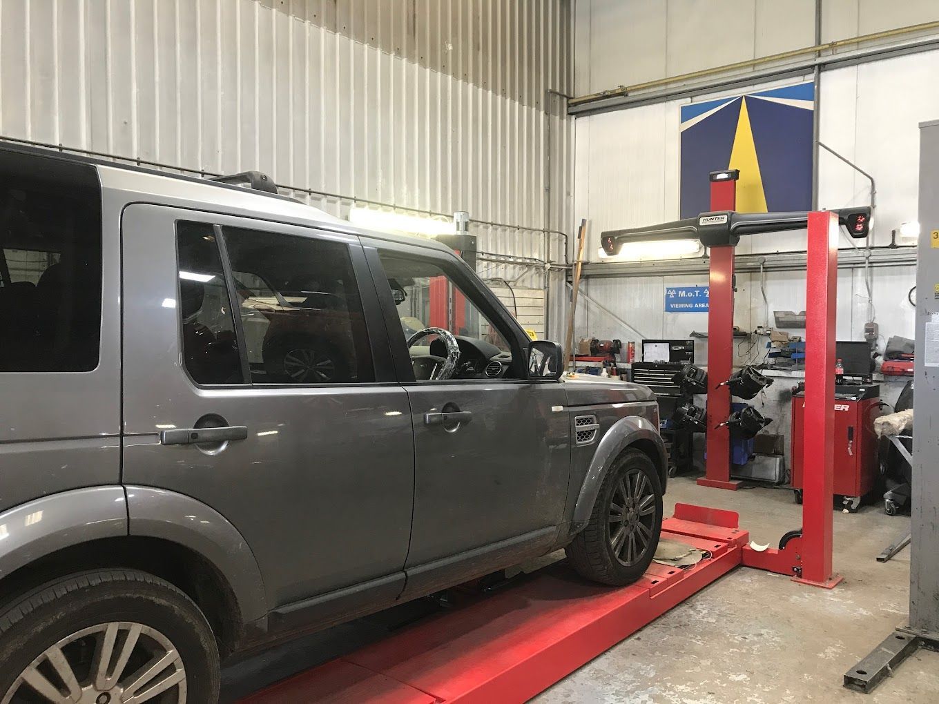 UK Select Accident Repair Centres | A car is sitting on a lift in a garage.