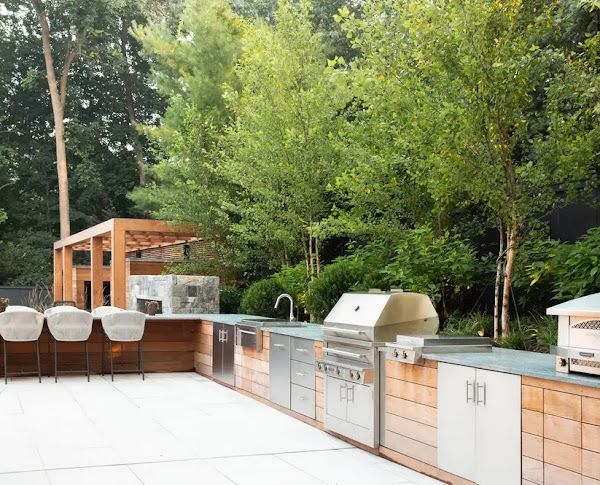 A large outdoor kitchen with stainless steel appliances and wooden cabinets.