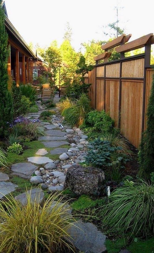 A stone path leading to a house with a wooden fence.