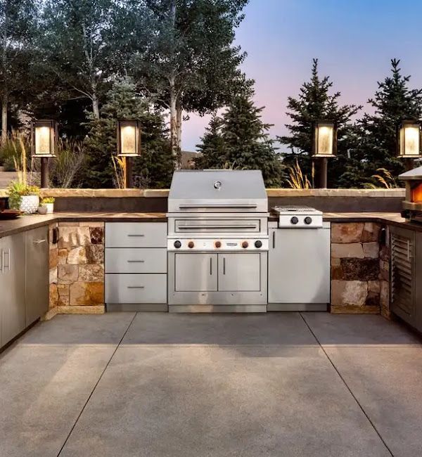 An outdoor kitchen with a stainless steel grill and cabinets
