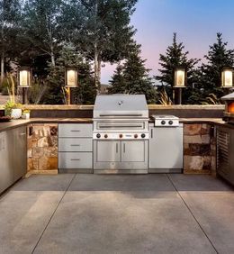 An outdoor kitchen with a stainless steel grill and cabinets