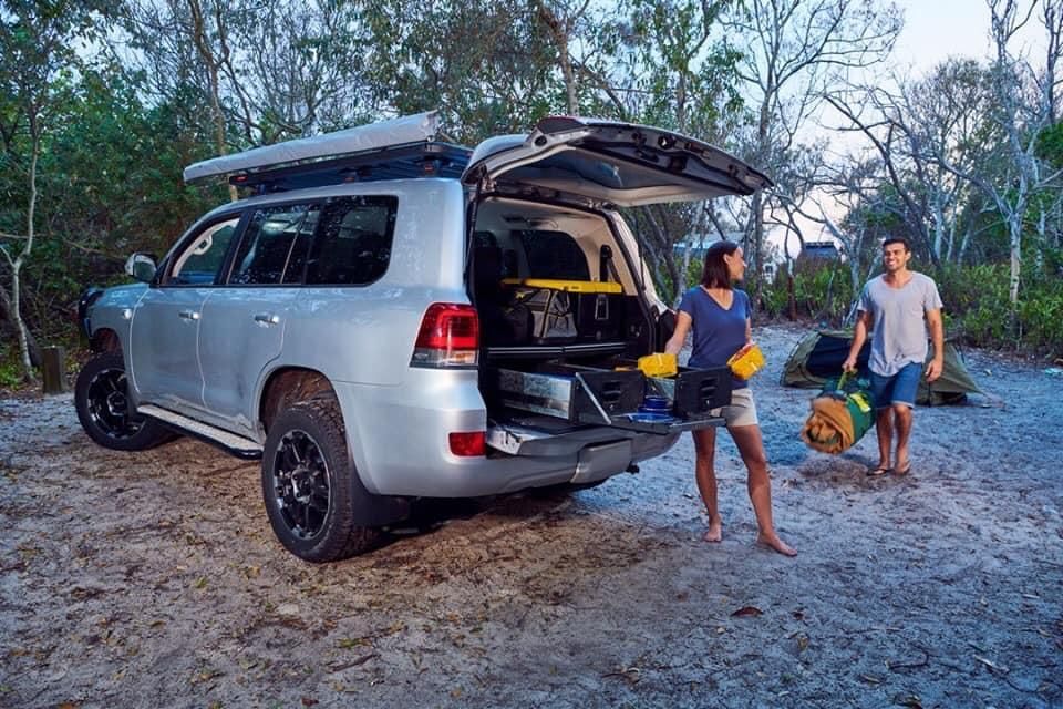 A Man And A Woman Are Standing Next To A Silver SUV With The Trunk Open — TJM Dubbo In Dubbo, NSW
