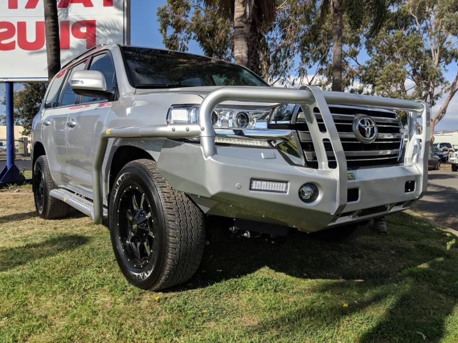 A Silver Toyota Land Cruiser Is Parked In The Grass In Front Of A Sign — TJM Dubbo In Nyngan, NSW