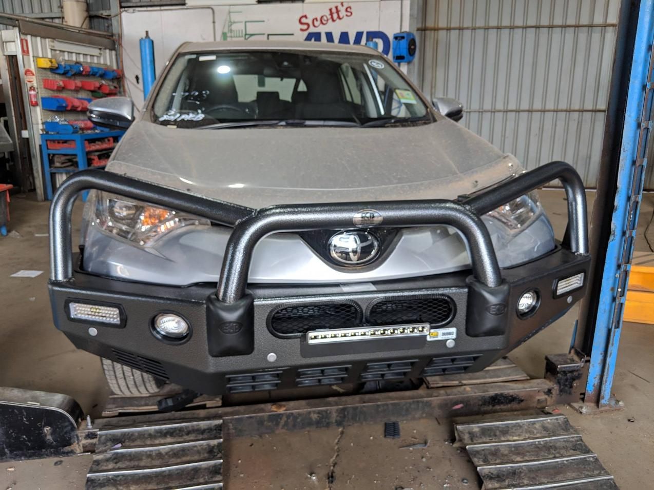 A Toyota Hilux Is Sitting On A Lift In A Garage — TJM Dubbo In Walgett, NSW