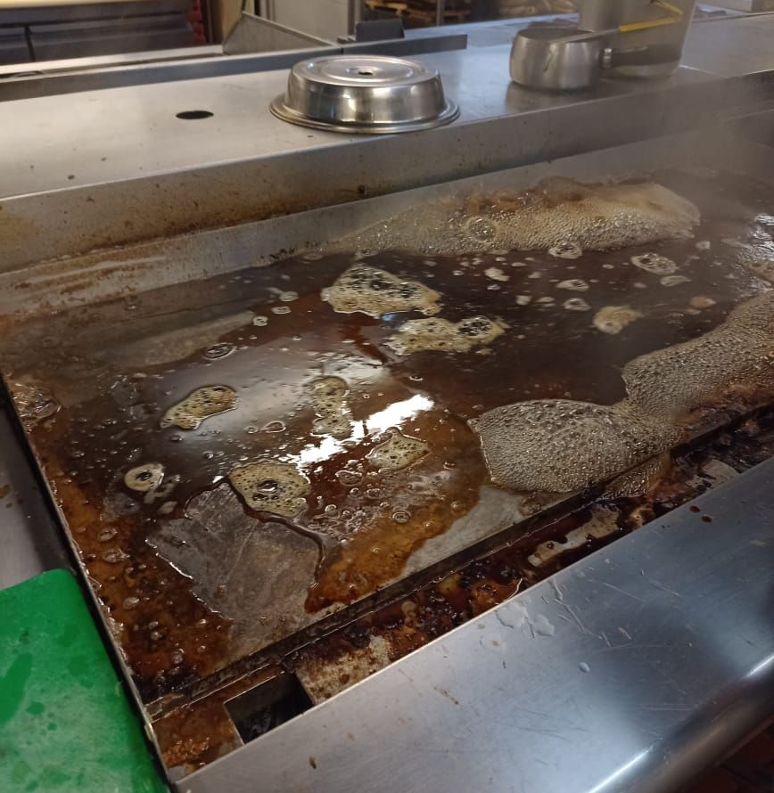 Gabinetes de cocina blancos con encimeras y fregadero negros. Vitrinas e iluminación bajo los gabinetes.