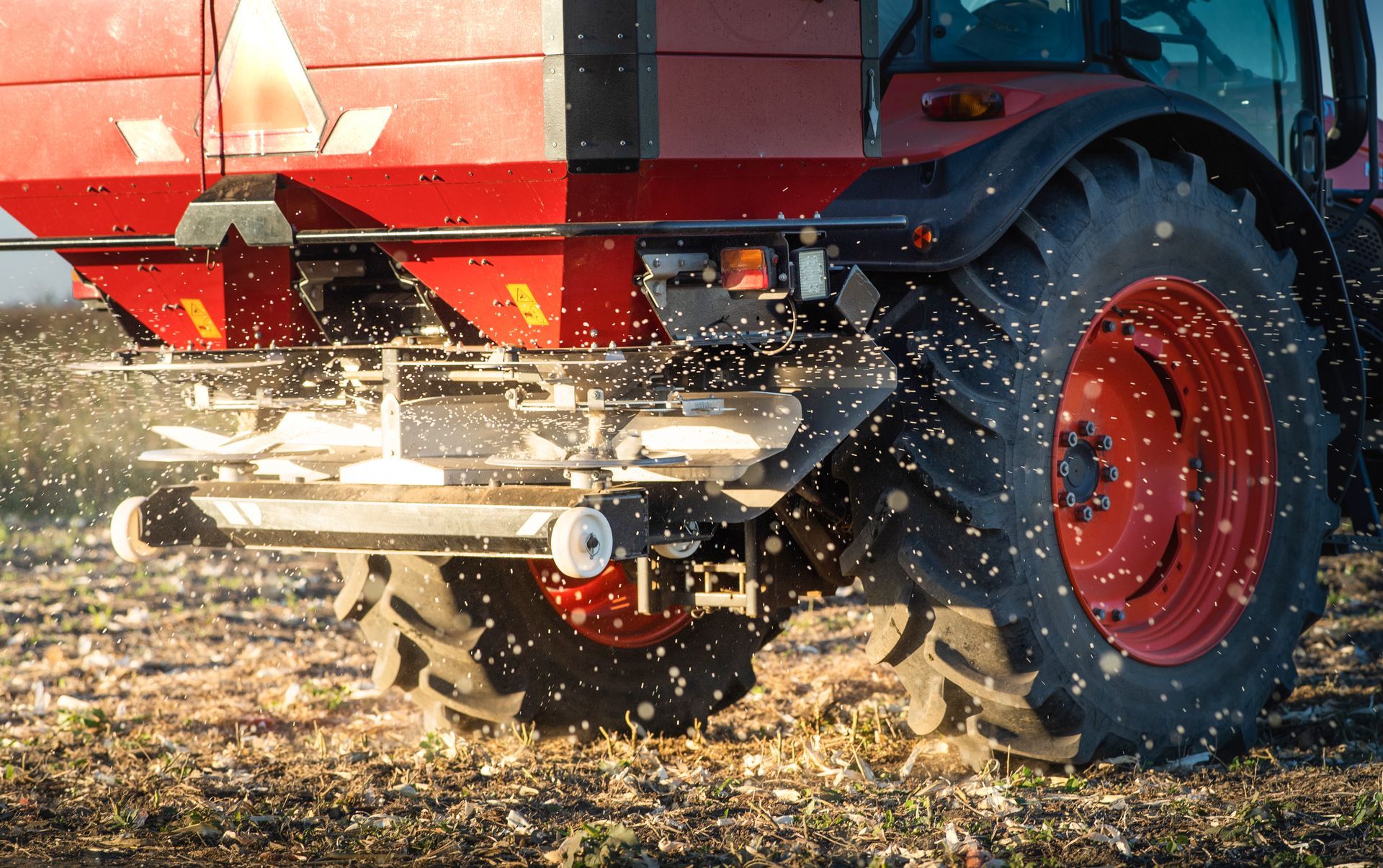 A tractor is spreading artificial fertiliser on agricultural land.