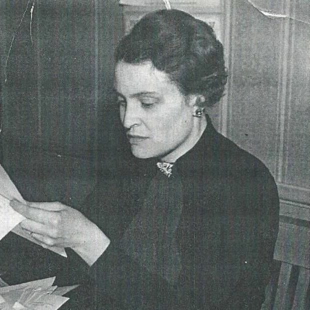 A woman wearing glasses and a black shirt smiles for the camera