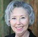 A woman with gray hair is smiling for the camera.