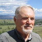 A man with a beard is standing in front of a field.