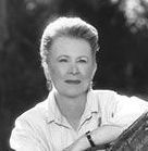 A black and white photo of a woman sitting on a bench with her arms crossed.