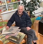 A man is sitting at a table holding a stack of records.