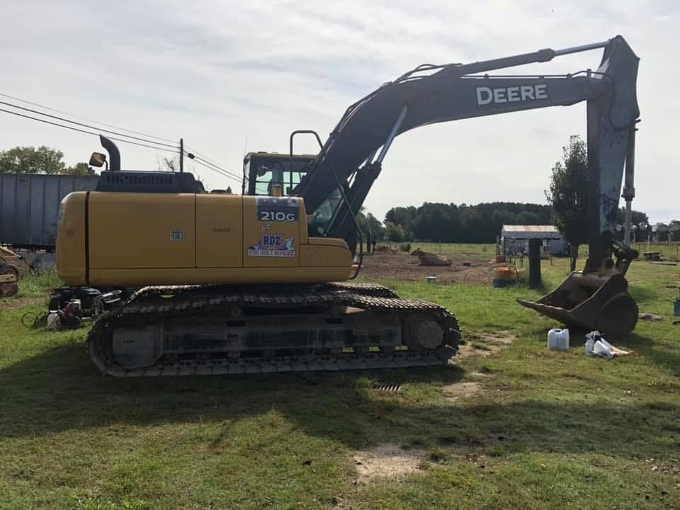 A large deere excavator is parked in a grassy field.