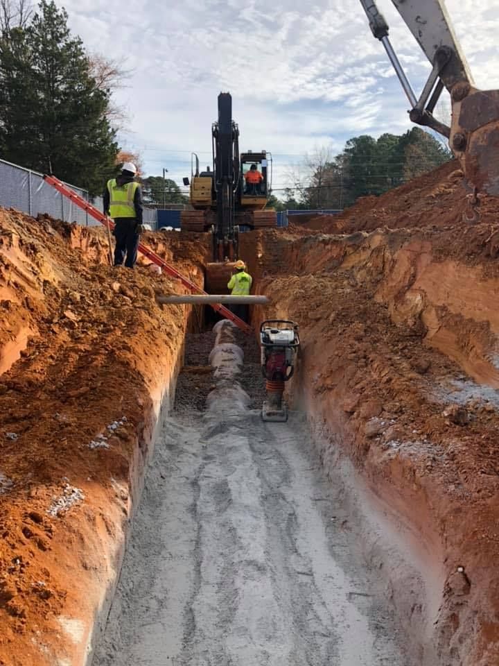 A group of construction workers are digging a trench in the dirt.