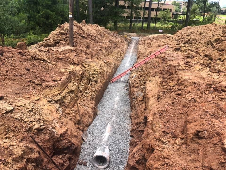 A pipe is being installed in a trench in the dirt.