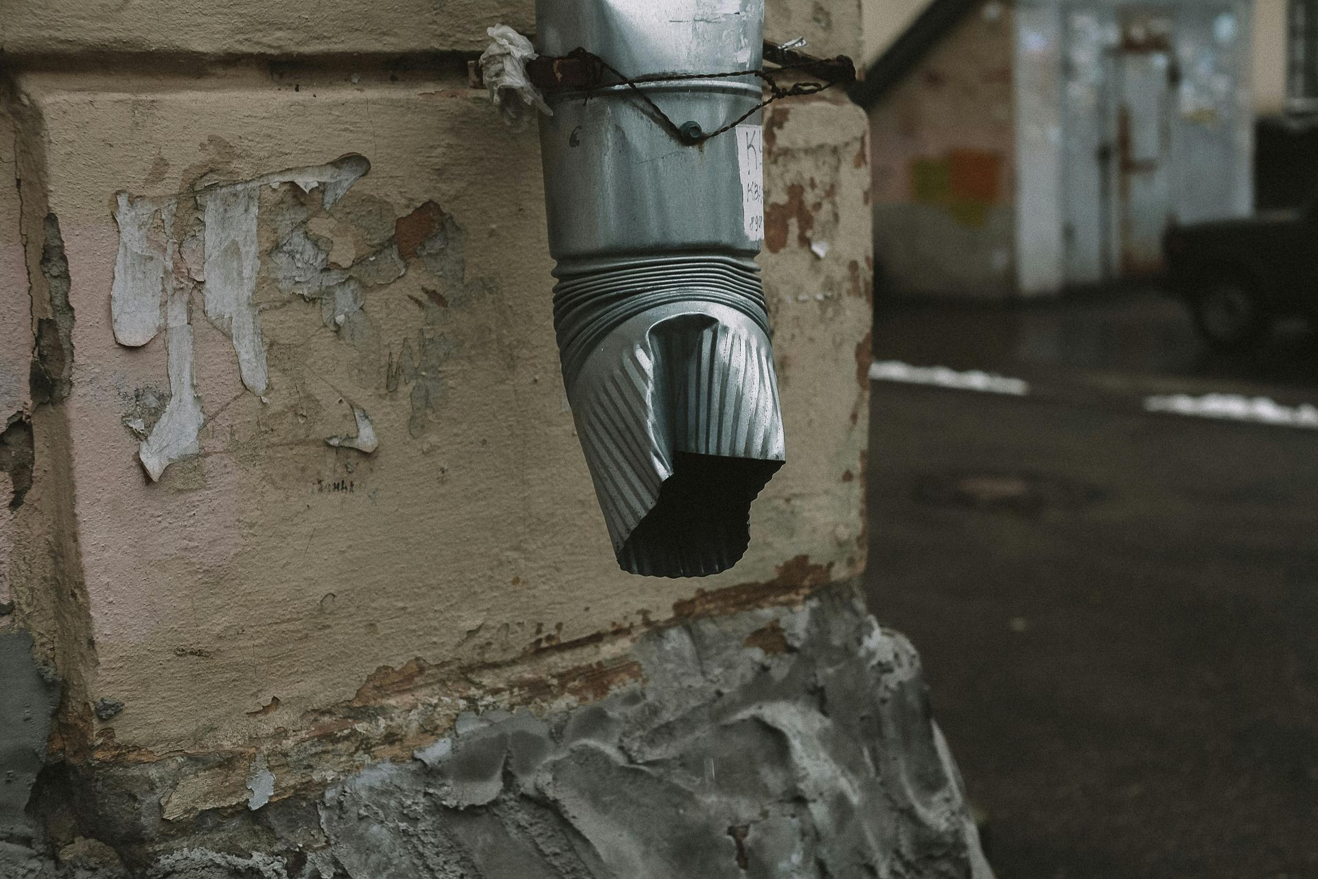 A metal pipe is attached to a brick wall.