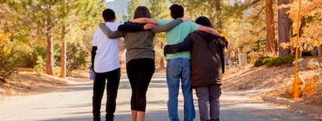 A Group of People are Walking Down a Road with their Arms Around Each Other.