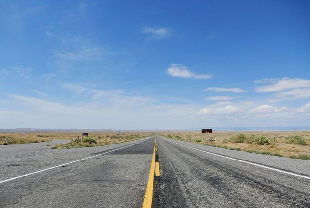 An empty road in the desert with a blue sky in the background