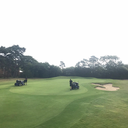 A group of people are working on a golf course.