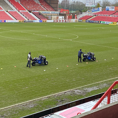 A soccer field with two tractors on it