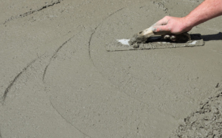 Concrete finisher using hand tool to finish wet concrete