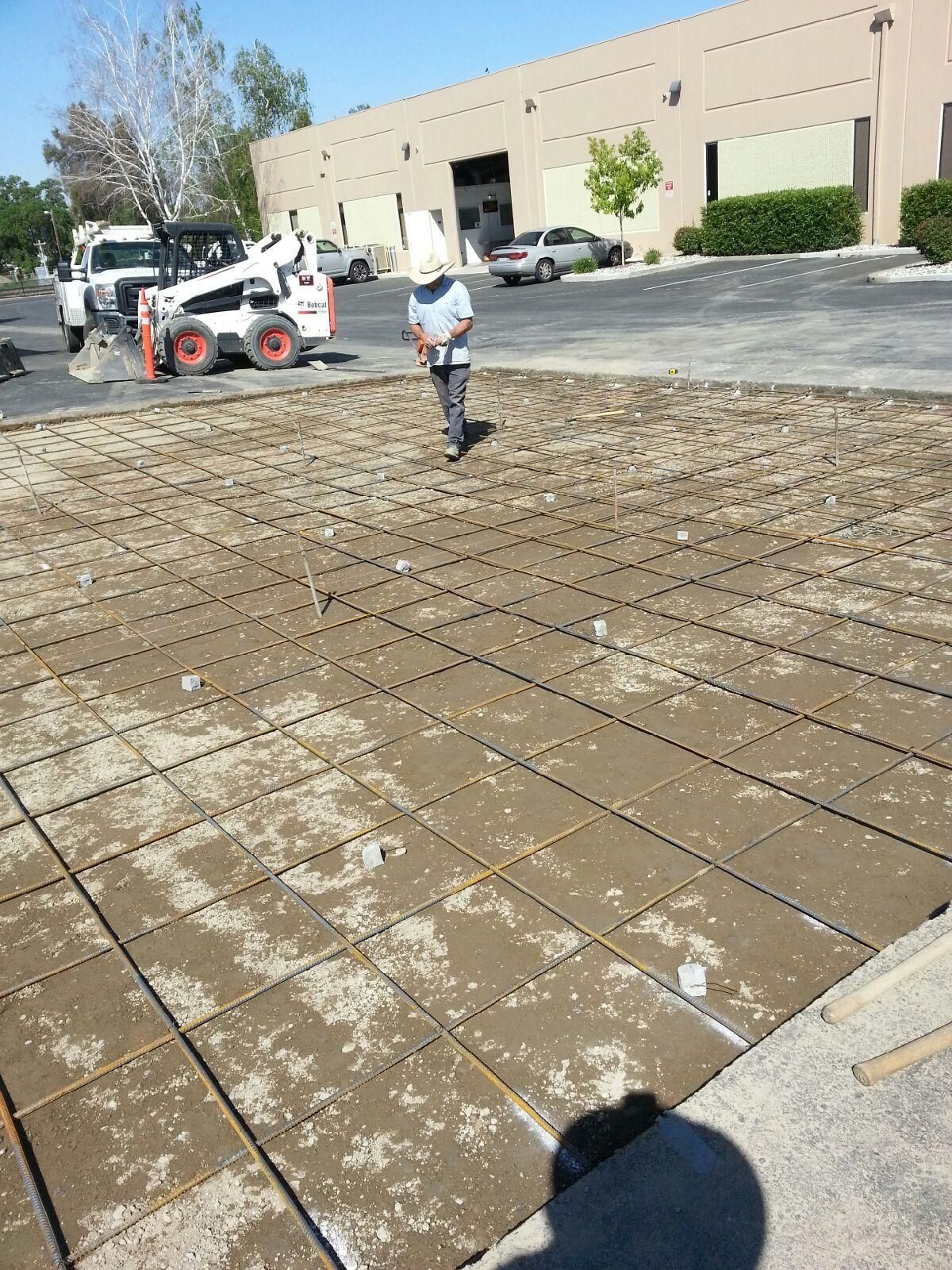 A man is standing in a parking lot with a bobcat in the background.