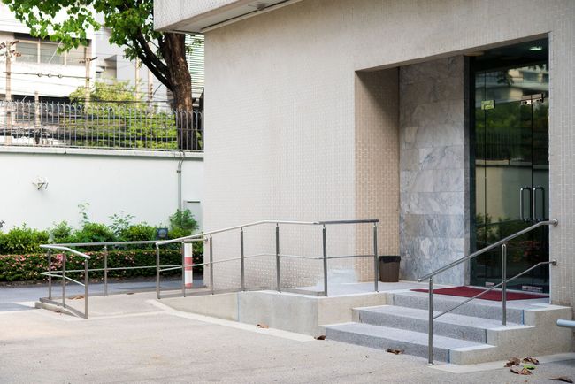 A building with stairs leading up to it and a stainless steel railing.