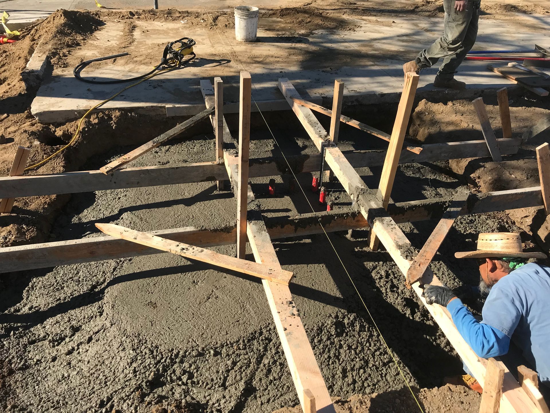 A man wearing a hat is laying concrete on a construction site.