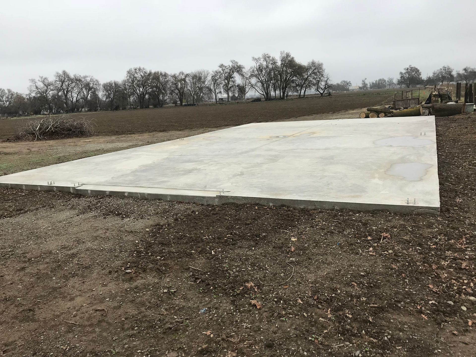A large concrete slab is sitting in the middle of a dirt field.