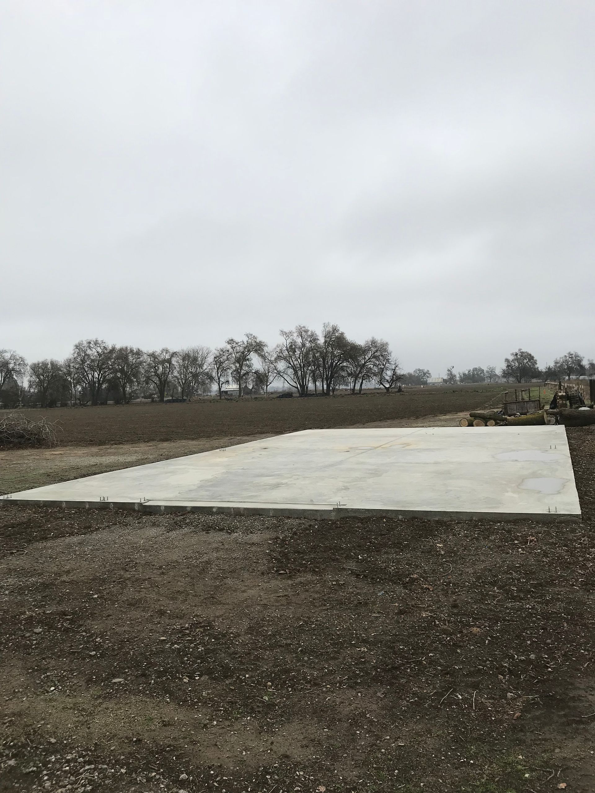 A large concrete slab is sitting in the middle of a dirt field.