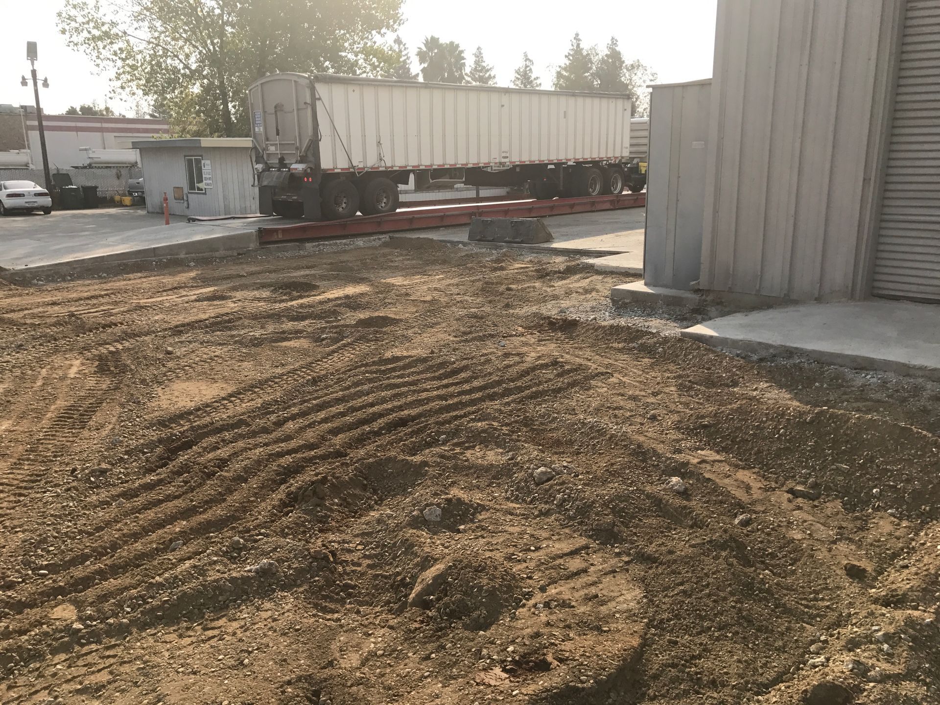 A semi truck is sitting on a scale in a dirt field.