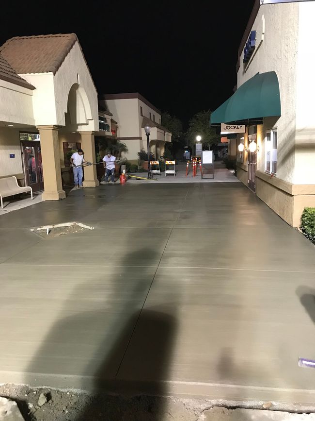 A concrete driveway is being built in front of a building at night.