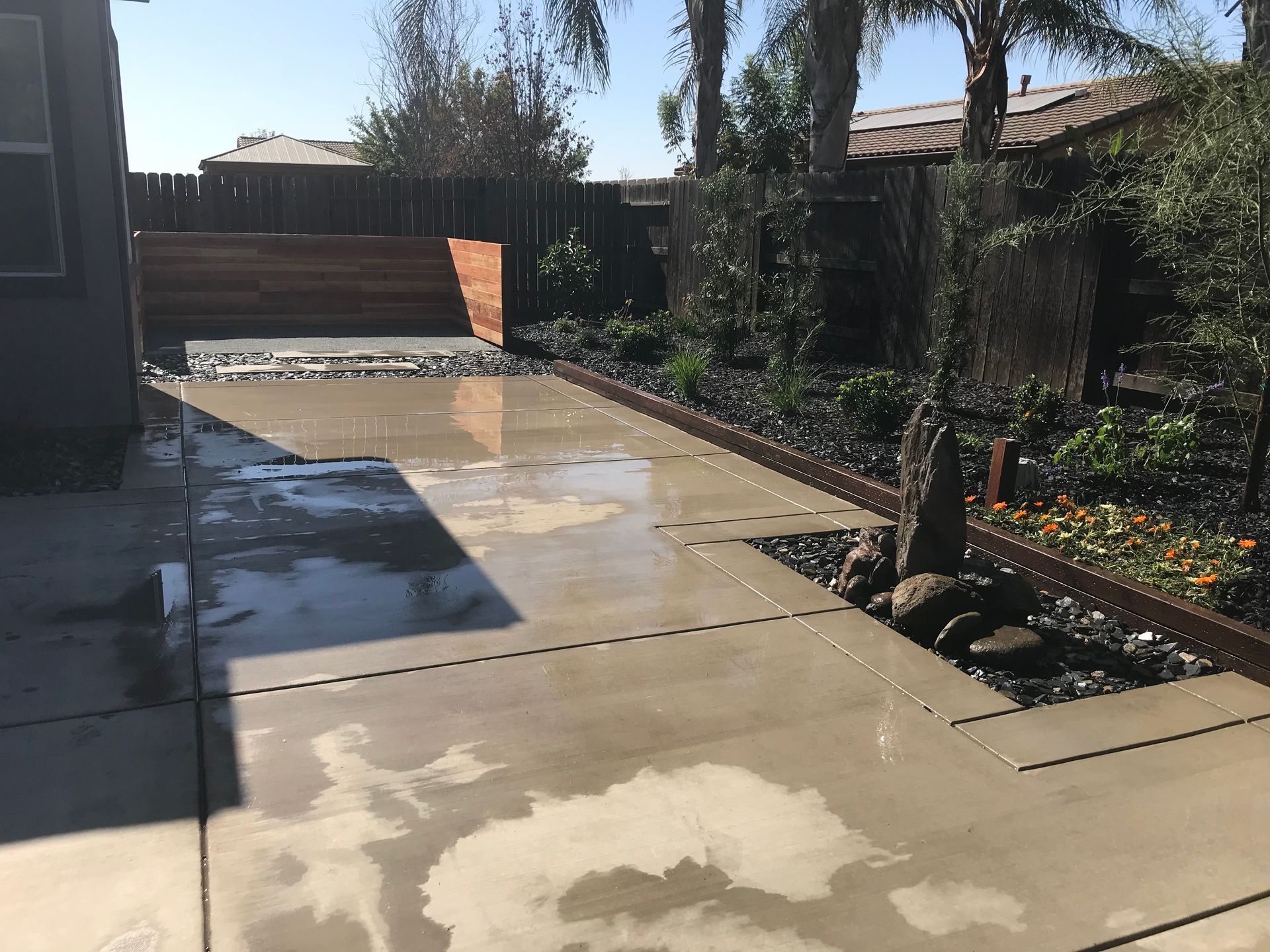 A concrete driveway with a fence and trees in the background