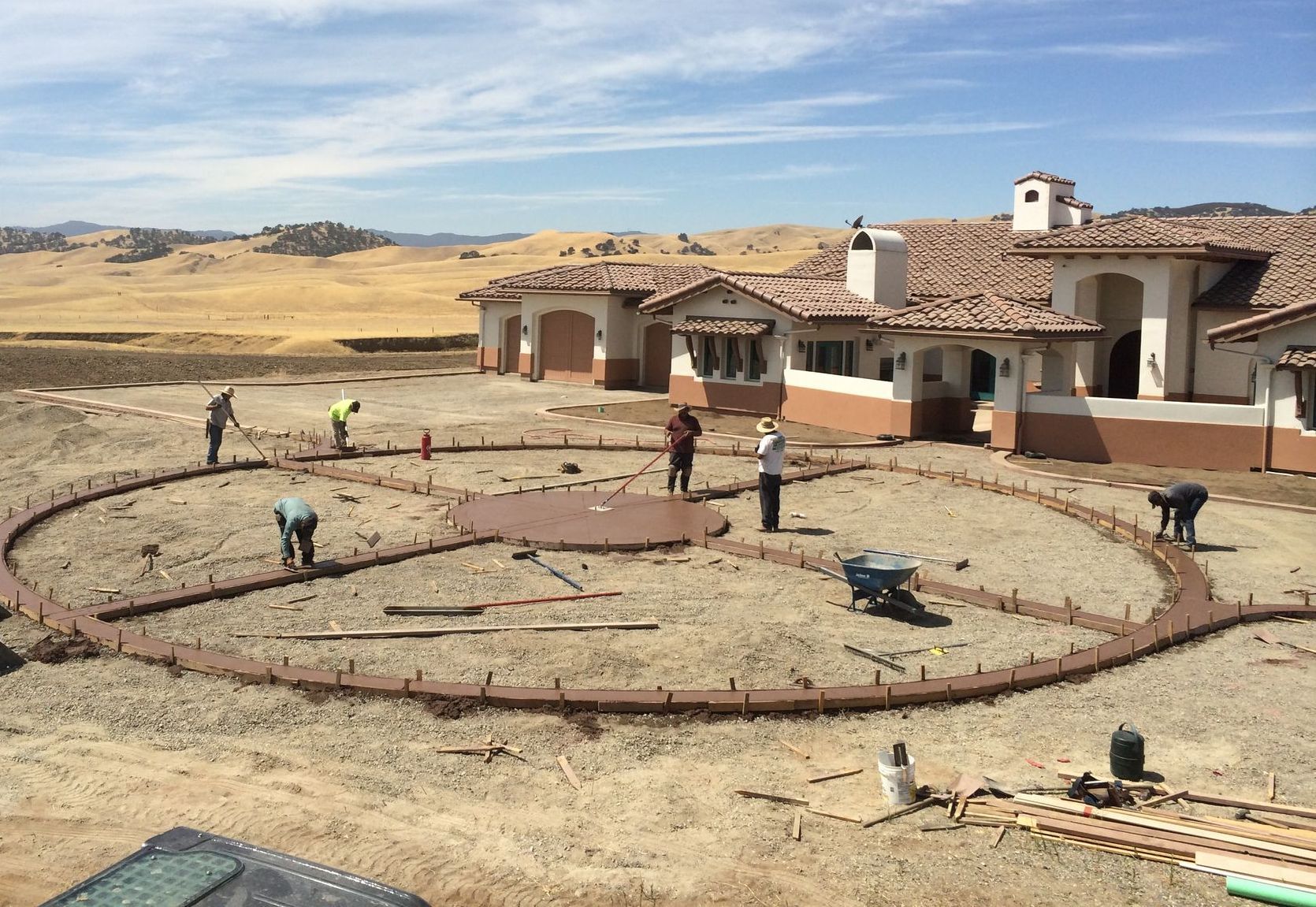 A group of people are working on a concrete circle in front of a house