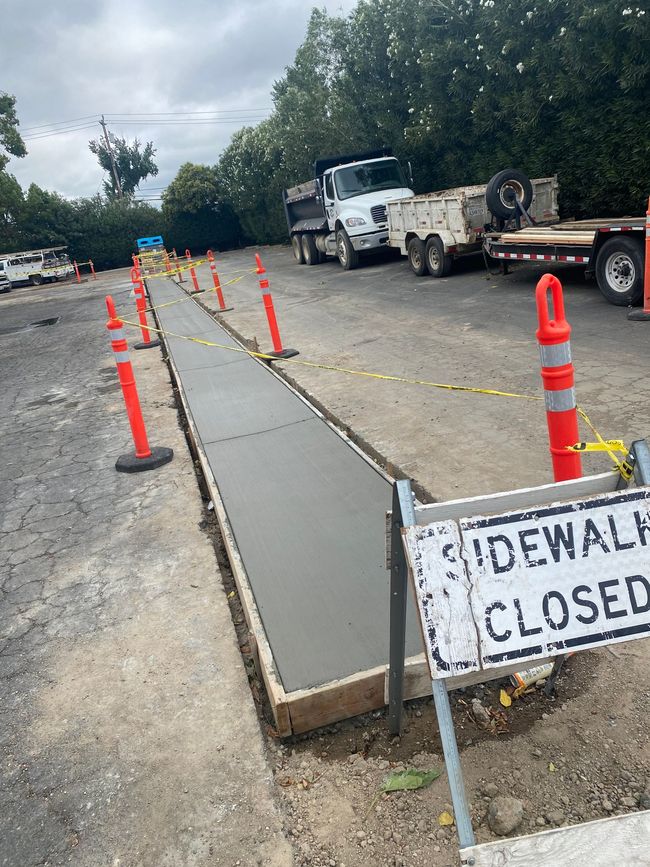 A sidewalk is being built in a parking lot with a sign that says sidewalk closed.