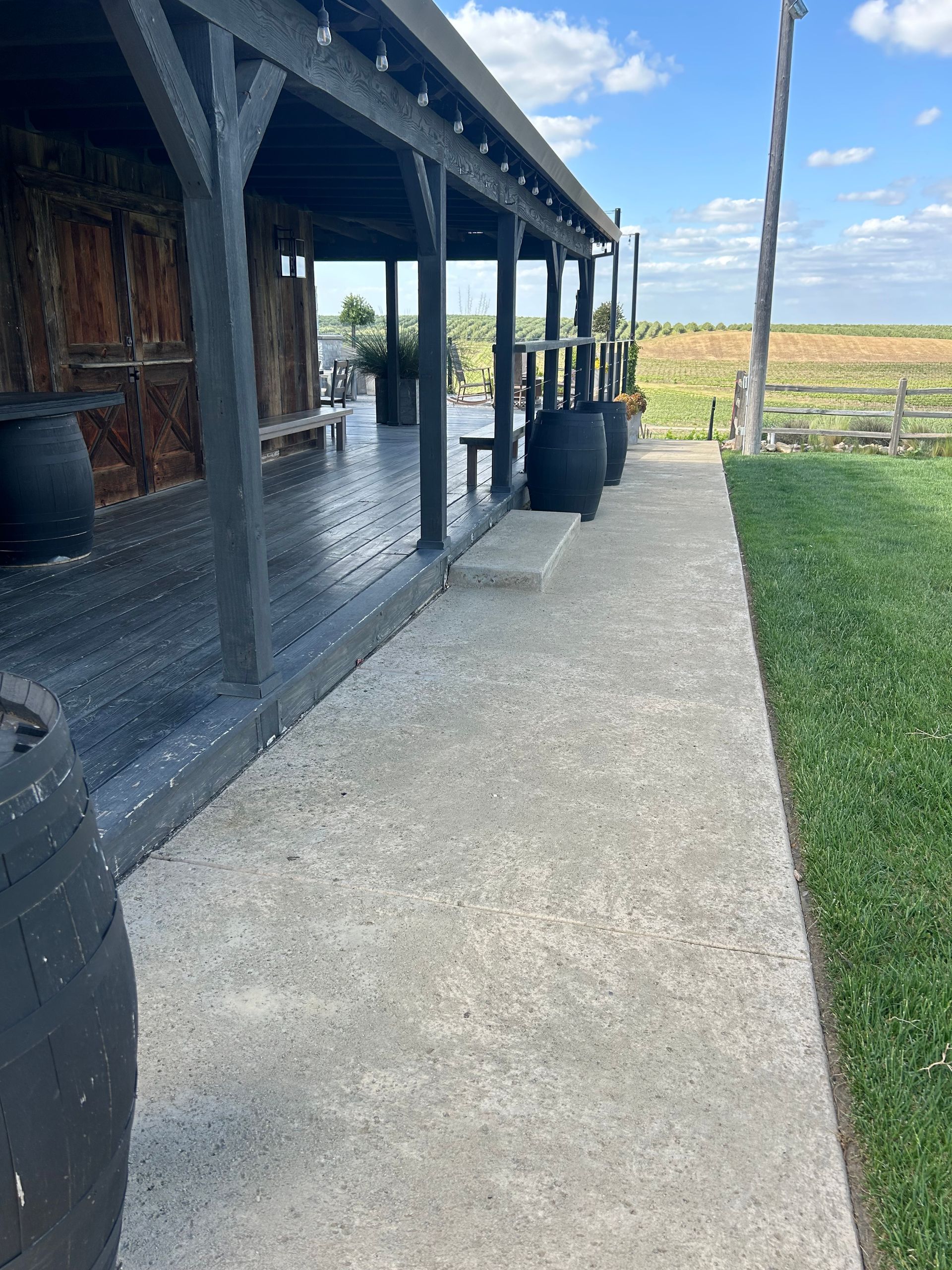 A concrete walkway leading to a wooden building with a porch.