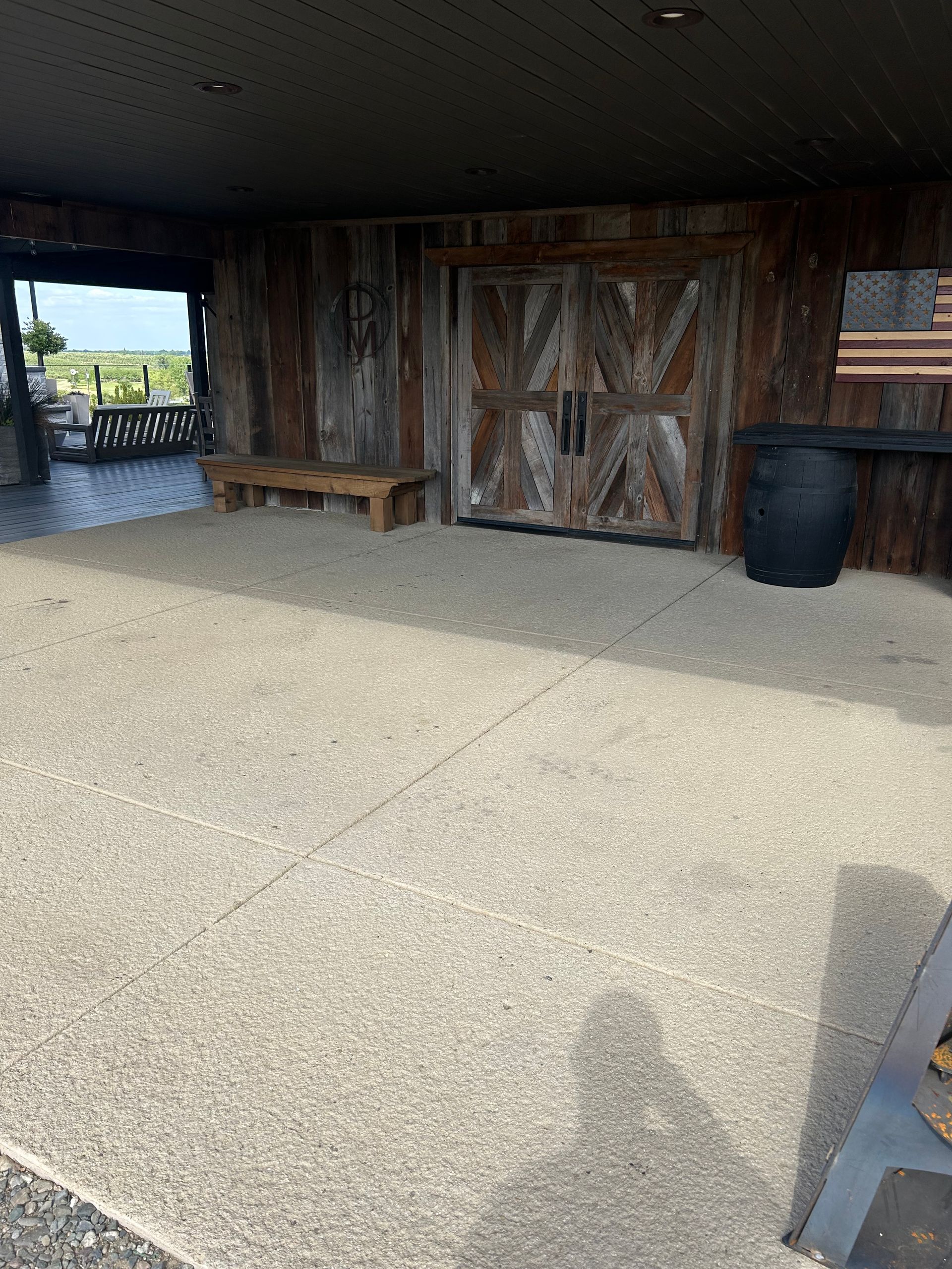 A patio with a wooden door and an american flag on the wall.