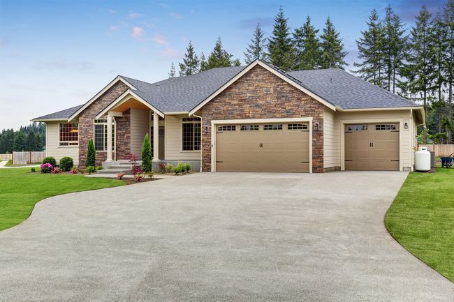 A large house with two garage doors and a driveway in front of it.