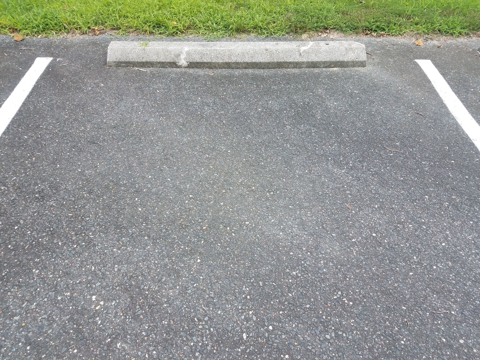 An empty parking lot with a curb and white lines.